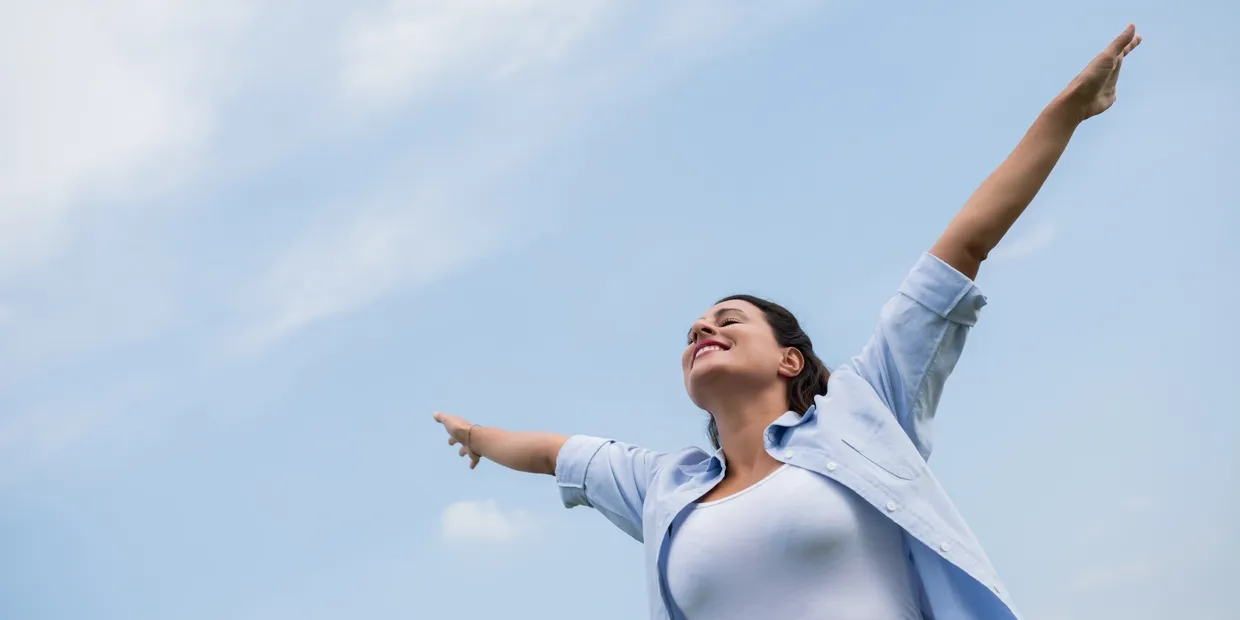 A woman is standing in the air with her arms outstretched.