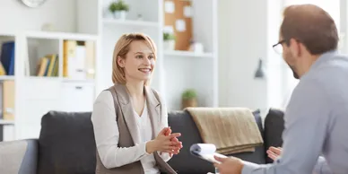 A woman sitting on the couch talking to someone.