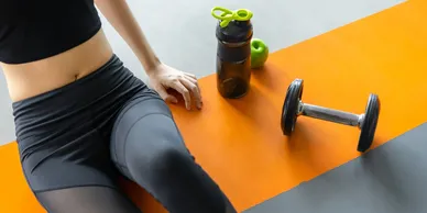 A person sitting on the ground with a bottle and weight.